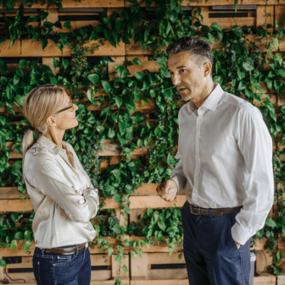 Standing businessman and businesswoman talking in green office